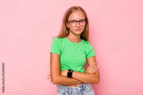 Caucasian teen girl isolated on pink background suspicious, uncertain, examining you.