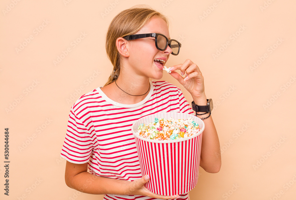Little caucasian girl eating popcorn isolated on beige background Little caucasian girl eating popcorn isolated on beige background