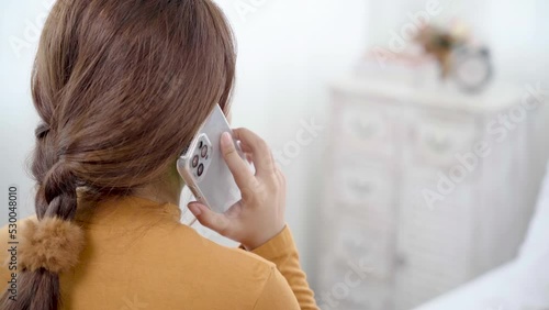 Closeup of Happy Teenager girl talking on smartphone with best friend at home, woman uses  phone to communicate with customers. Joyful female speaking on mobile phone. Back view.
