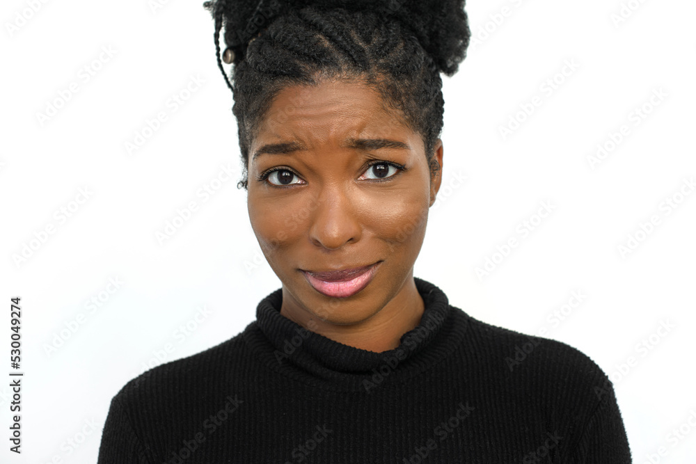 Uncertain African American woman in studio. Female model in turtleneck with curly hair looking at camera, on verge of tears. Portrait, studio shot, emotion concept Uncertain African American woman in studio. Female model in turtleneck with curly hair looking at camera, on verge of tears. Portrait, studio shot, emotion concept