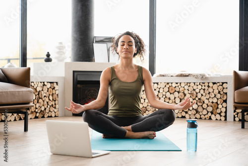 Young african yogi athlete woman in sporty clothes meditating in lotus position Fototapeta