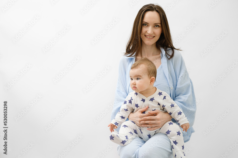 Φωτογραφία smiling mother with baby on her lap sitting on white background, portrait of wom