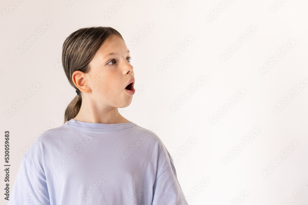 Portrait of astonished preteen girl wearing blue T-shirt looking away. Surprised Caucasian child posing against white background. Surprise concept Portrait of astonished preteen girl wearing blue T-shirt looking away. Surprised Caucasian child posing against white background. Surprise concept