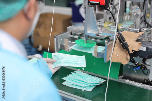 Inspector or worker hands with nitrile gloves doing quality of mask and medical face mask production line, Industry and factory concept.