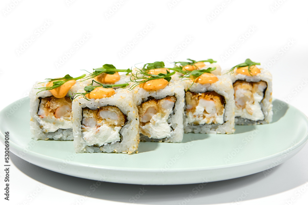 Maki sushi with sesame outside, tempura shrimp inside topped spicy sauce and microgreens. Spicy shrimp maki roll on ceramic plate isolated on white background Sushi roll with crispy prawn on plate Maki sushi with sesame outside, tempura shrimp inside topped spicy sauce and microgreens. Spicy shrimp maki roll on ceramic plate isolated on white background Sushi roll with crispy prawn on plate
