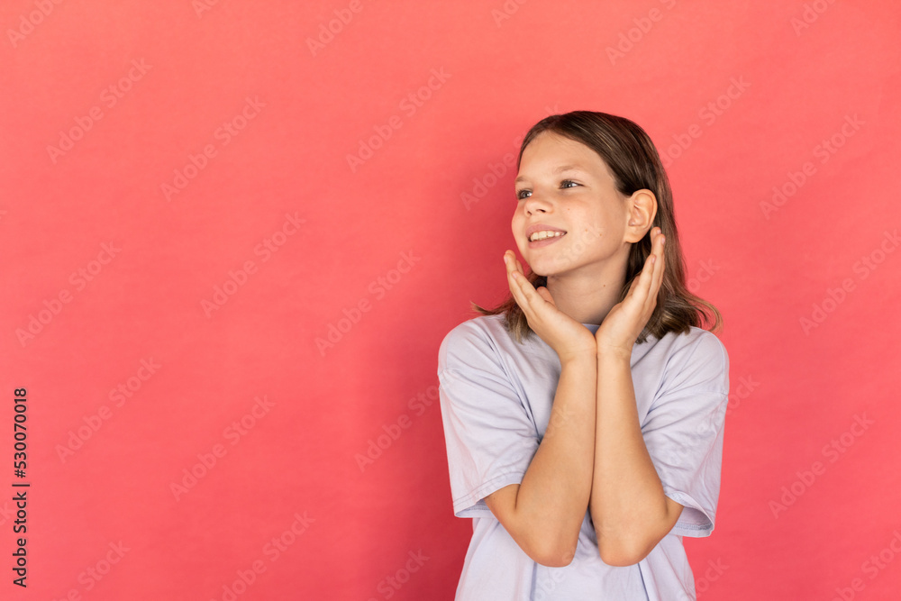 Portrait of happy girl looking at something with admiration. Preteen Caucasian child wearing blue T-shirt looking away and smiling against red background. Admiration concept Portrait of happy girl looking at something with admiration. Preteen Caucasian child wearing blue T-shirt looking away and smiling against red background. Admiration concept