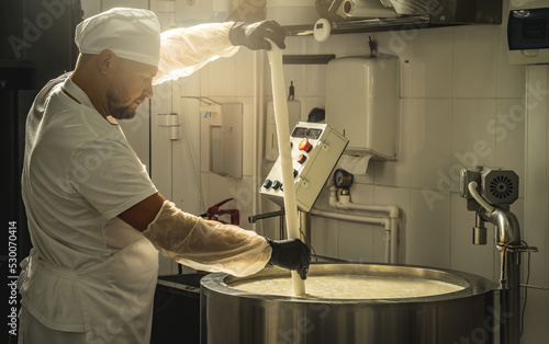Man is a cheese maker in the process of producing different varieties of cheese in the industry. Milk cheese making