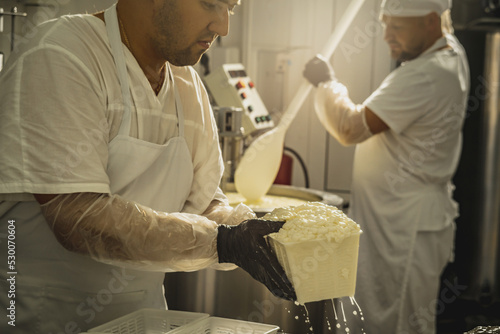 Man is a cheese maker in the process of producing different varieties of cheese in the industry. Milk cheese making photo