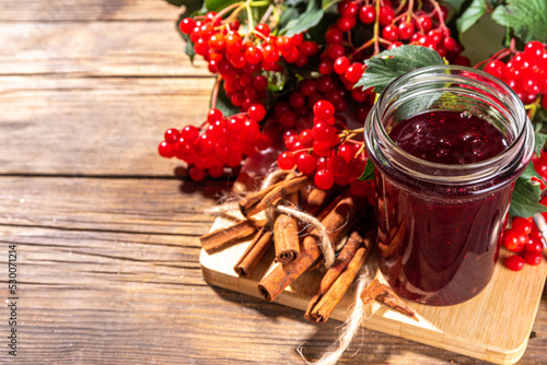 Autumn jam recipe, conservation and harvest season. Homemade red jam from organic viburnum berries, with fresh berries on twigs and cinnamon