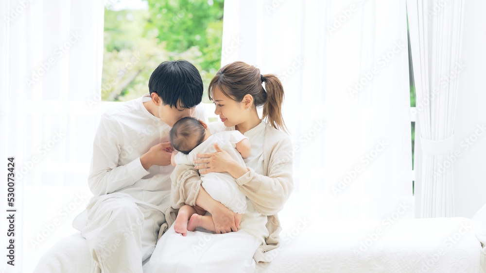 部屋でくつろぐ赤ちゃんを抱いたカップル 家族イメージ 部屋でくつろぐ赤ちゃんを抱いたカップル 家族イメージ