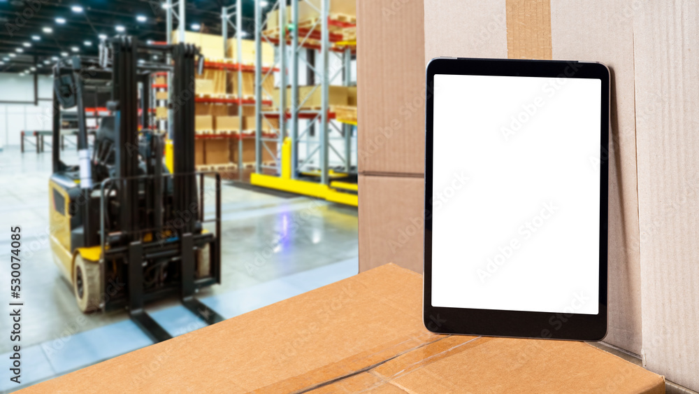Warehouse applications. Tablet with blank screen. Tablet computer on boxes. Application for tracking warehouse balances concept. Warehouse fulfillment technologies. Blurred forklift behind tablet Warehouse applications. Tablet with blank screen. Tablet computer on boxes. Application for tracking warehouse balances concept. Warehouse fulfillment technologies. Blurred forklift behind tablet