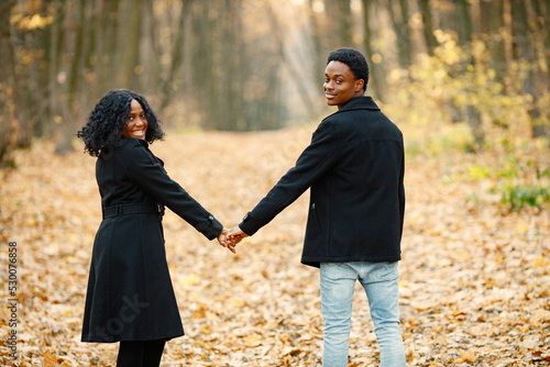 Loving black couple walking in park and enjoying autumn day © prostooleh