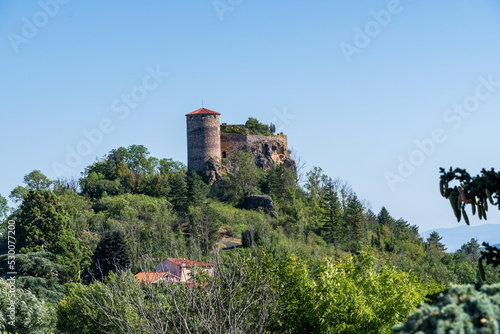 Gros plan du château de Busséols perché en haut de sa montagne avec sa tour de défense par une journée d'été sur le chemin de randonnée de Mirefleurs dans le puy de dôme