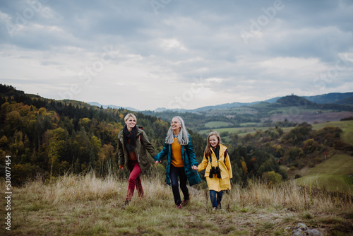 Small girl with mother and grandmother hiking outoors in nature.