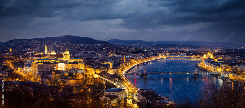 Elevated panoramic skyline view of Budapest, Hungary, during winter evening time with Buda Castle Royal Palace, Szechenyi Chain Bridge, Parliament at the Danube river