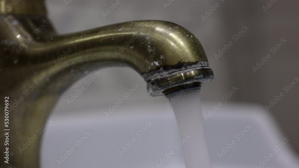 The Dirty Old Water Faucet In A Bathroom, Water Is Starting Pouring, Close-up. Vintage Bronze Tap Turning On. 60 FPS, 4k, ProRes The Dirty Old Water Faucet In A Bathroom, Water Is Starting Pouring, Close-up. Vintage Bronze Tap Turning On. 60 FPS, 4k, ProRes