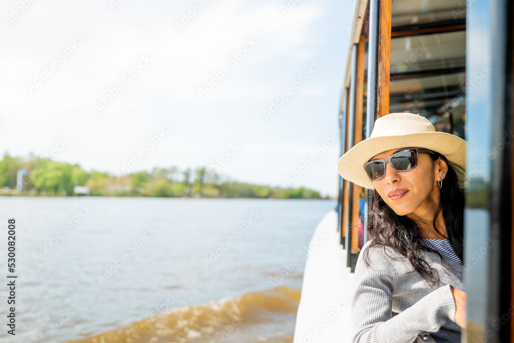 Mujer viajera con sobrero navegando en barco por el rio