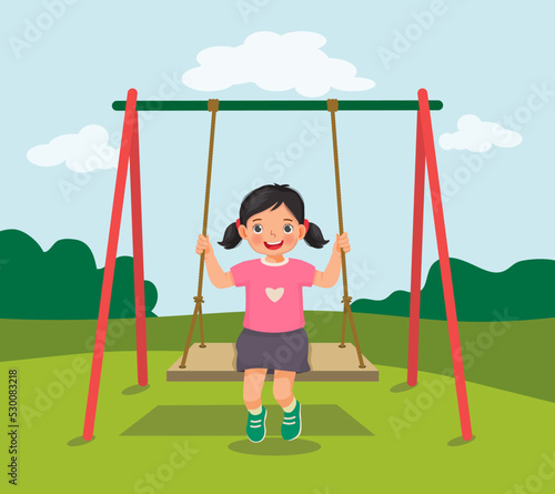 cute little girl swinging and having fun on rope wooden swing in playground