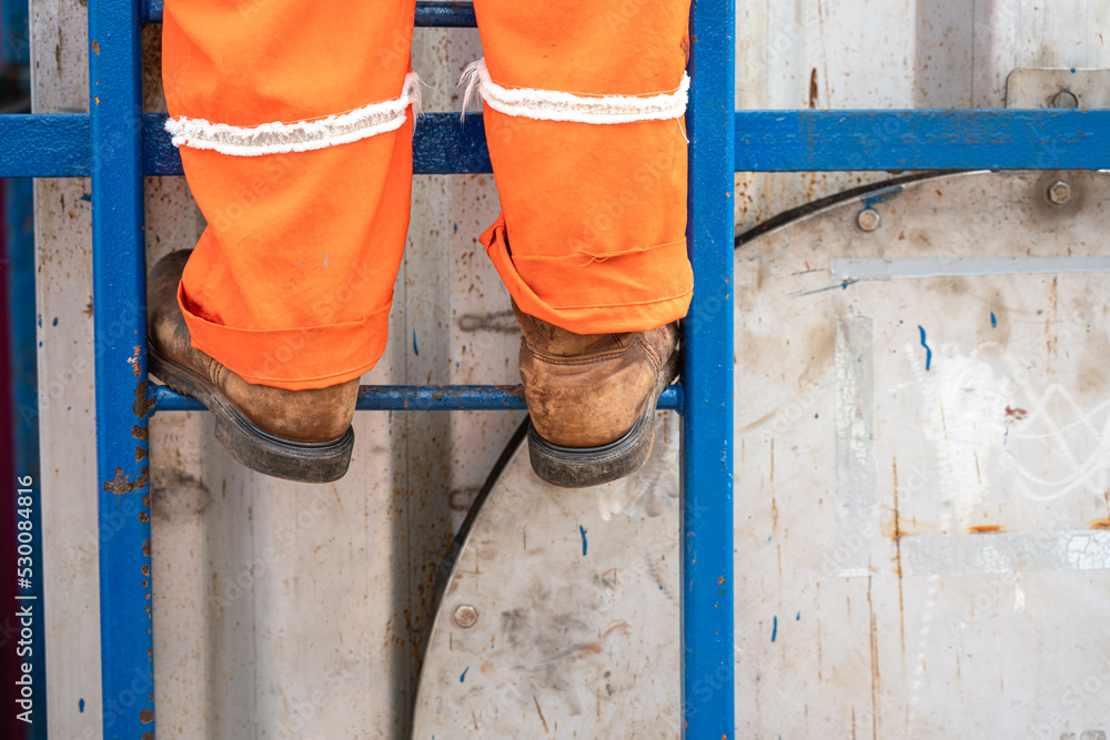 Action of a construction worker is climbing on the platform ladder. An