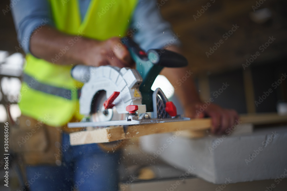 Close-up of construction worker working with eletric saw inside wooden construction of house, diy eco-friendly homes concept.