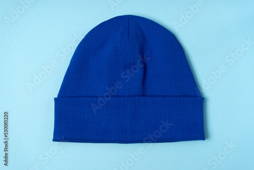 Blue beanie hat on a light blue background. Trendy youth knitted hat. Top view