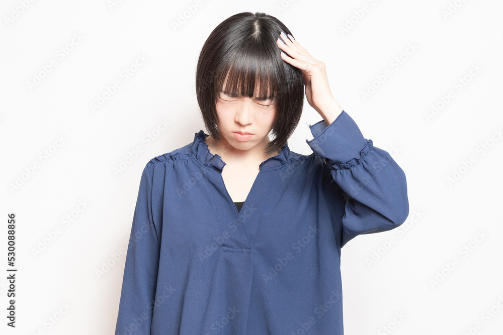 白バックの前に立って、困っている若い女性