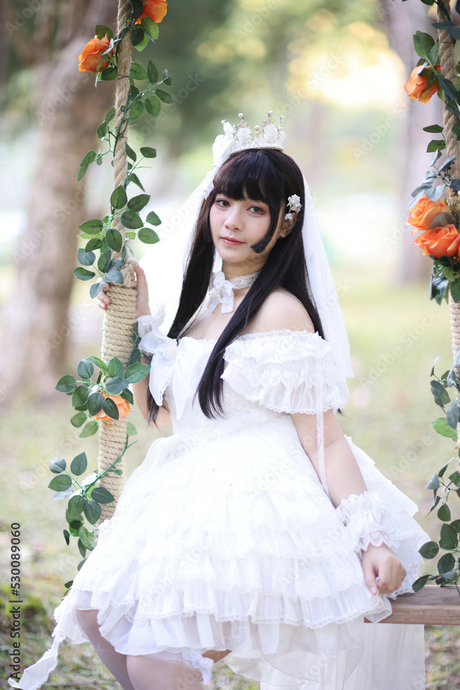 Beautiful young woman with white lolita dress with european garden Japanese fashion Beautiful young woman with white lolita dress with european garden Japanese fashion