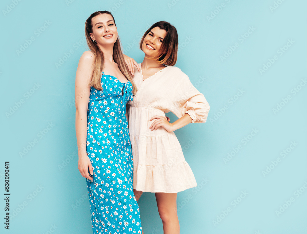 Two young beautiful smiling brunette hipster female in trendy summer shorts clothes. Sexy carefree women posing near blue wall. Positive models having fun. Cheerful and happy. Hugging Two young beautiful smiling brunette hipster female in trendy summer shorts clothes. Sexy carefree women posing near blue wall. Positive models having fun. Cheerful and happy. Hugging