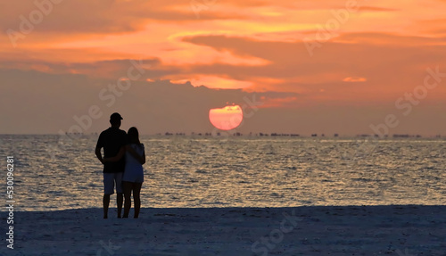 Beach lovers watch the sunset over Sanibel Island from Fort Myers Beach, Florida, USA. photo