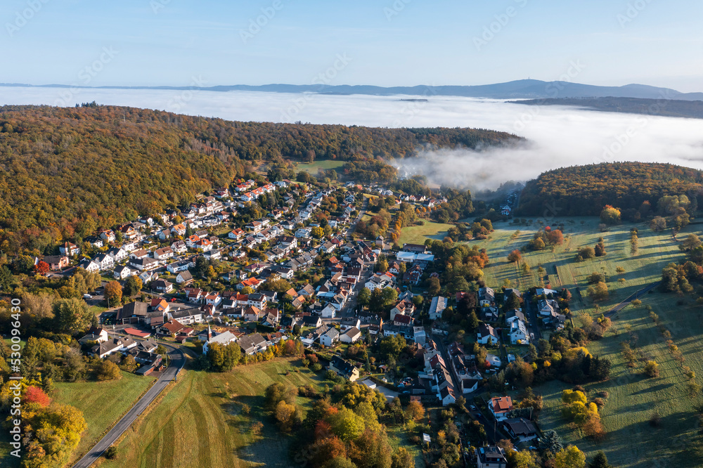 Aerial view of a small village in Taunus/Germany with morning fog over the valley