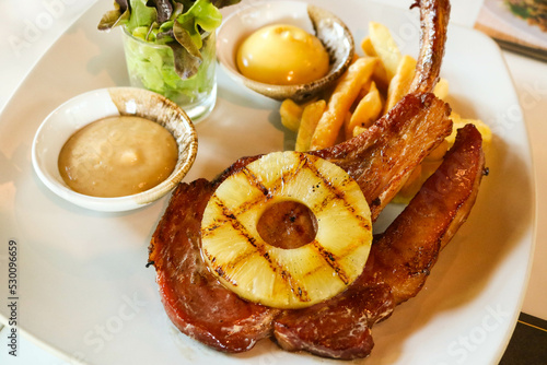 Grilled pork chop steak with pineapple, French fried and salad on white dish