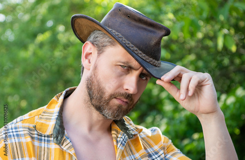 face of man in cowboy hat. sexy cowboy in checkered shirt. western cowboy wearing hat