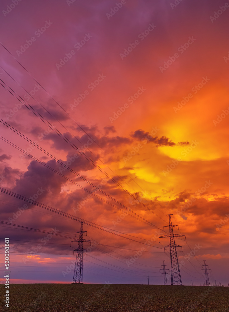 Electricity transmission power lines High voltage tower high-voltage lines. Transmission of electricity by means of supports through agricultural areas sunny day with landscape and dramatic clouds