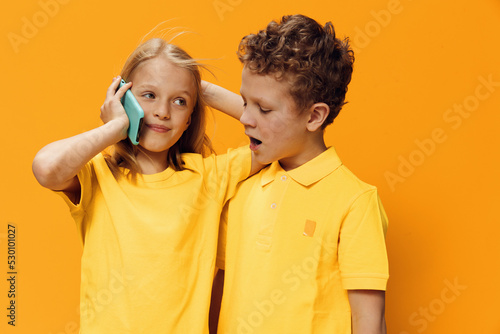 Bild auf Leinwand cute funny school-age children stand on a yellow background in bright clothes an