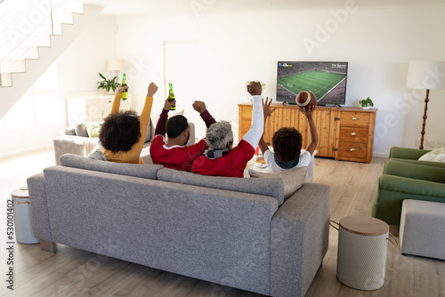 African american family sitting on the couch and watching football match on laptop