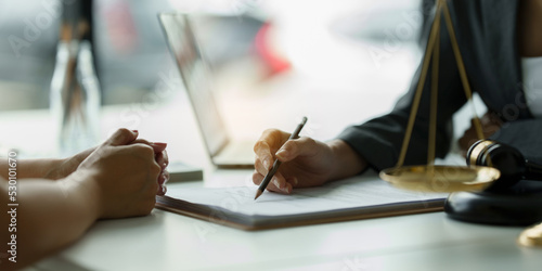 Foto Business woman and lawyers discussing contract papers with brass scale on wooden desk in office