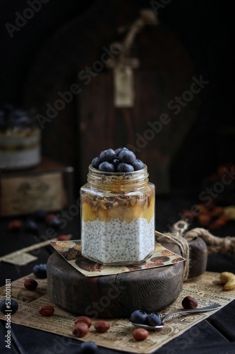 Chia pudding with nuts and blueberries in a jar on a wooden board