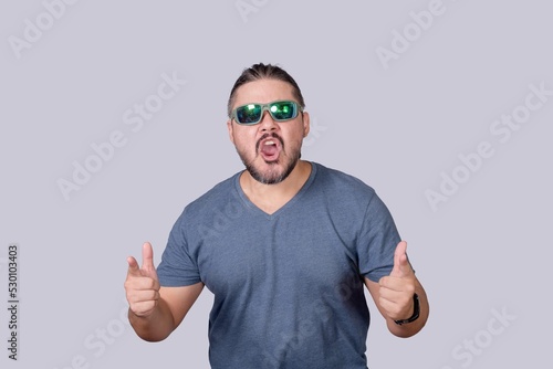 A man with long hair and wearing sunglasses acting tough and macho, pointing to the camera while yelling. Isolated on a gray background. photo