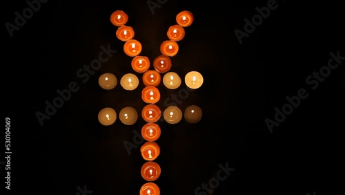 Japanese Yen Symbol Made of Burning Votive Candles Black Back Ground photo