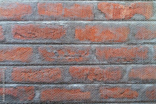 Steel net in front of brick wall