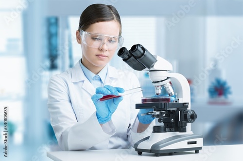 Happy young woman pharmacist mixing reagents at laboratory