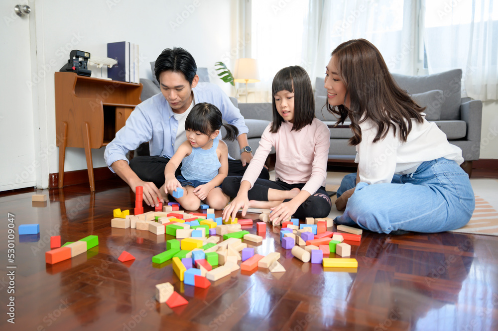 Asian family with children playing and building tower of colorful wooden toy blocks in living room at home, Educational game. Asian family with children playing and building tower of colorful wooden toy blocks in living room at home, Educational game.