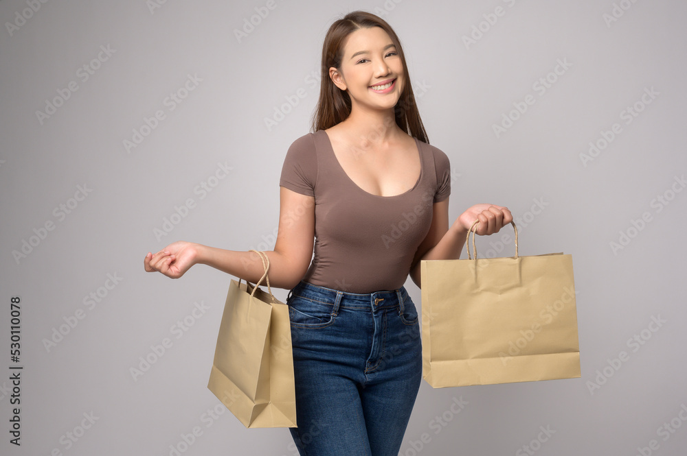 Young asian woman holding shopping bag over white background studio, shopping and finance concept. Young asian woman holding shopping bag over white background studio, shopping and finance concept.