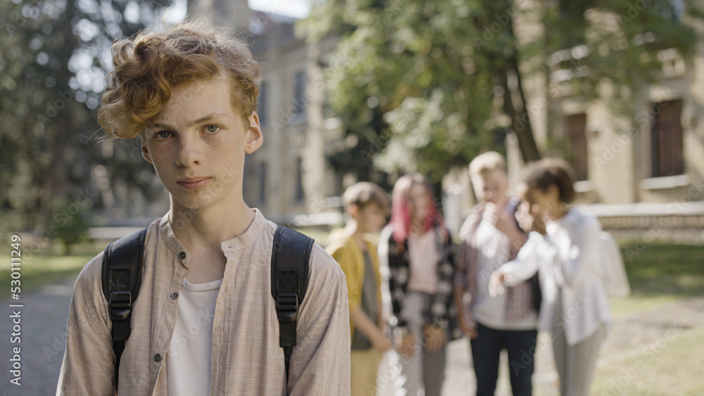 Cruel kids bullying unpopular classmate, teen boy suffering from