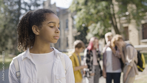Fotografija Group of children gossiping about African American school mate, bullying, abuse