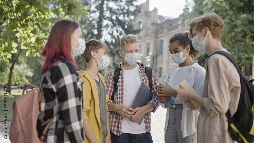 College students in protective face masks discussing classes on campus, education amid covid-19 pandemic