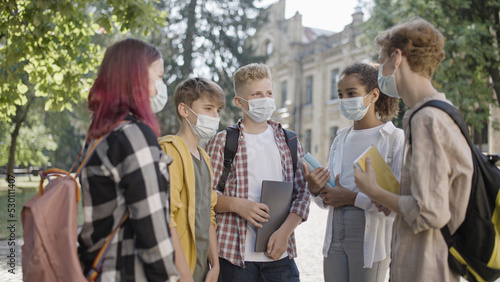 Group of school students wearing protective face masks on campus, pandemic safety