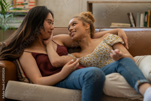 Obraz na plátně couple of multiracial young lesbian women, caressing on the sofa at home