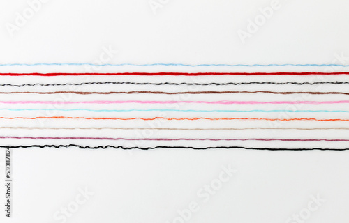multi-colored threads of yarn laid out on a white background, close-up