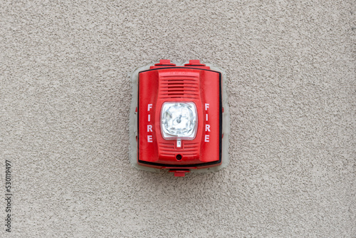Obraz na plátně Red fire alarm siren with flashing light strobe isolated on gray cement wall outdoor
